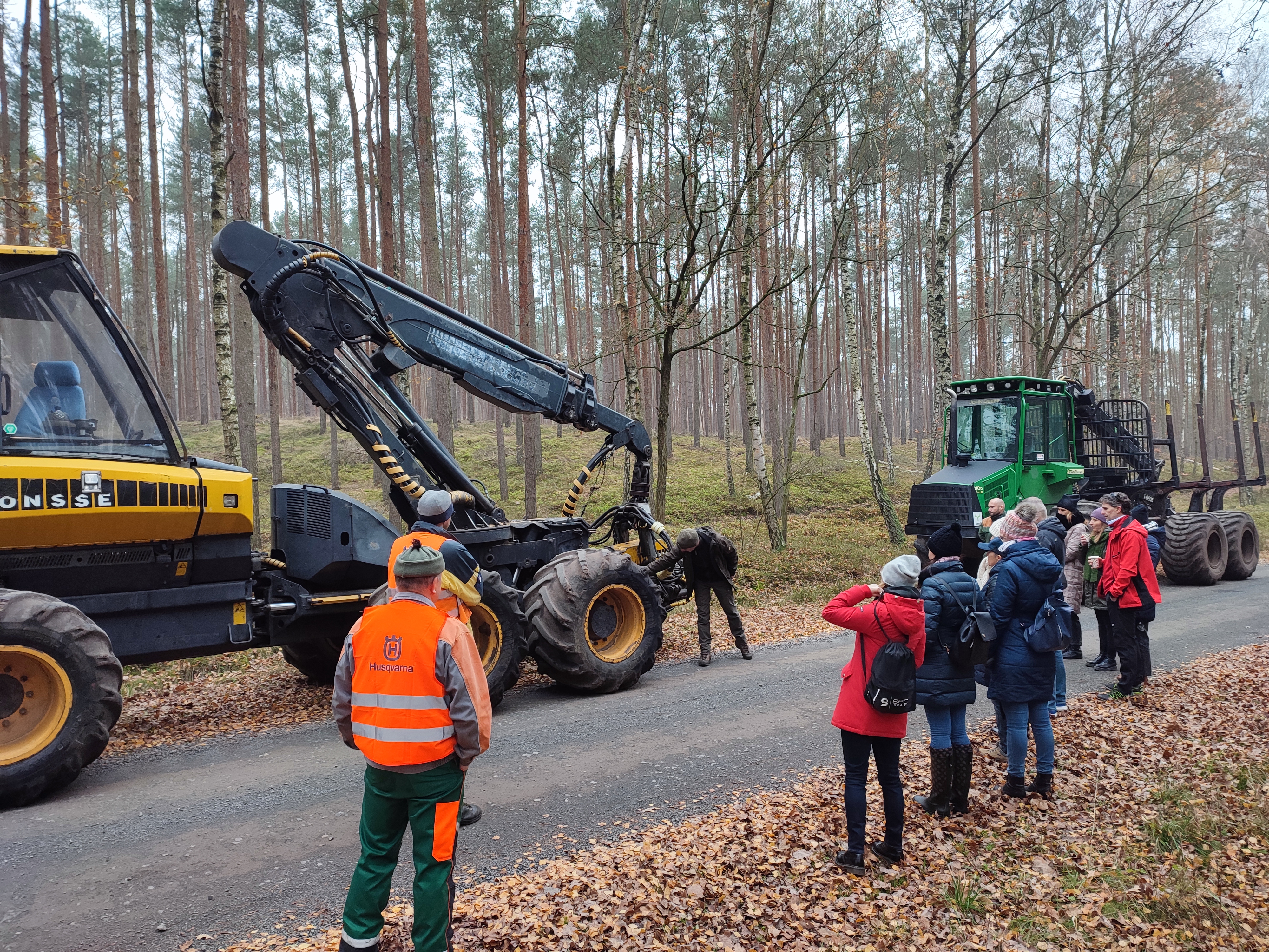 Zdjęcie przedstawia uczestników spotkania podczas pokazu maszyn służących do pozyskania drewna