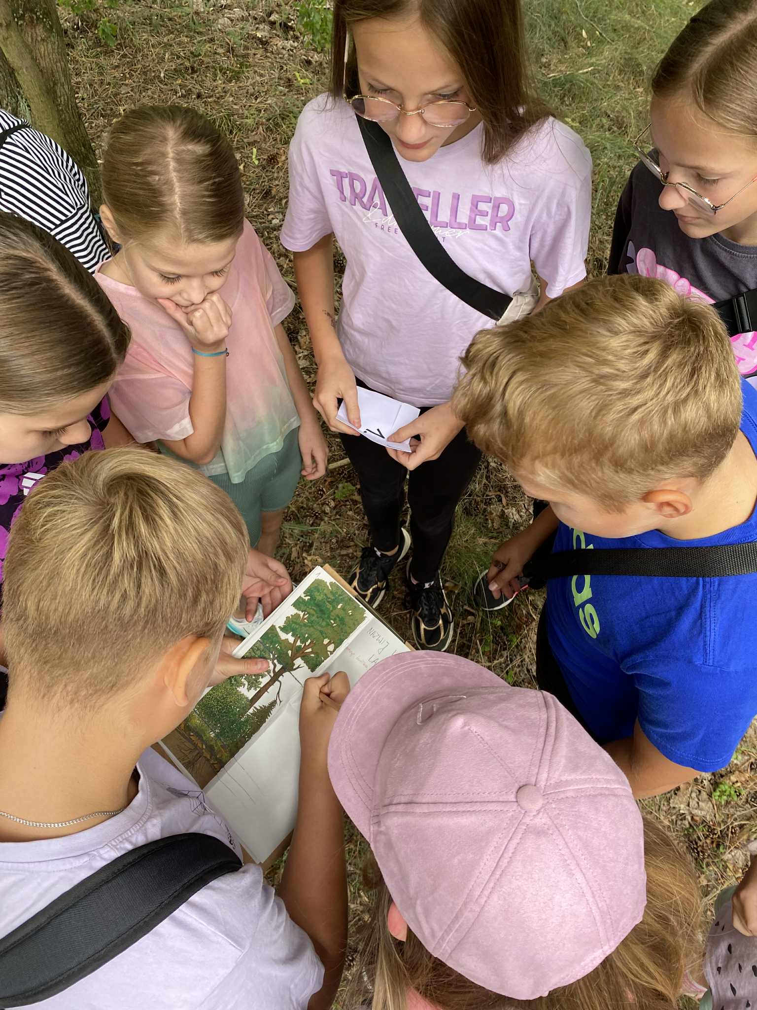 Zdjęcie przedstawia grupę dzieci stojących w okręgu i rozwiązujących wspólnie zadanie (fot. M. Prętkowska)