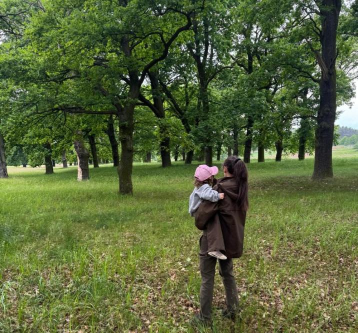 Zdjęcie&#x20;przedstawia&#x20;kobietę&#x20;-&#x20;leśnika&#x20;z&#x20;dzieckiem&#x20;na&#x20;ręku&#x2c;&#x20;stojącą&#x20;tyłem&#x2c;&#x20;w&#x20;tle&#x20;las&#x2e;&#x20;&#x28;fot&#x2e;&#x20;archiwum&#x20;prywatne&#x2c;&#x20;N&#x2e;Nabzdyk&#x29;